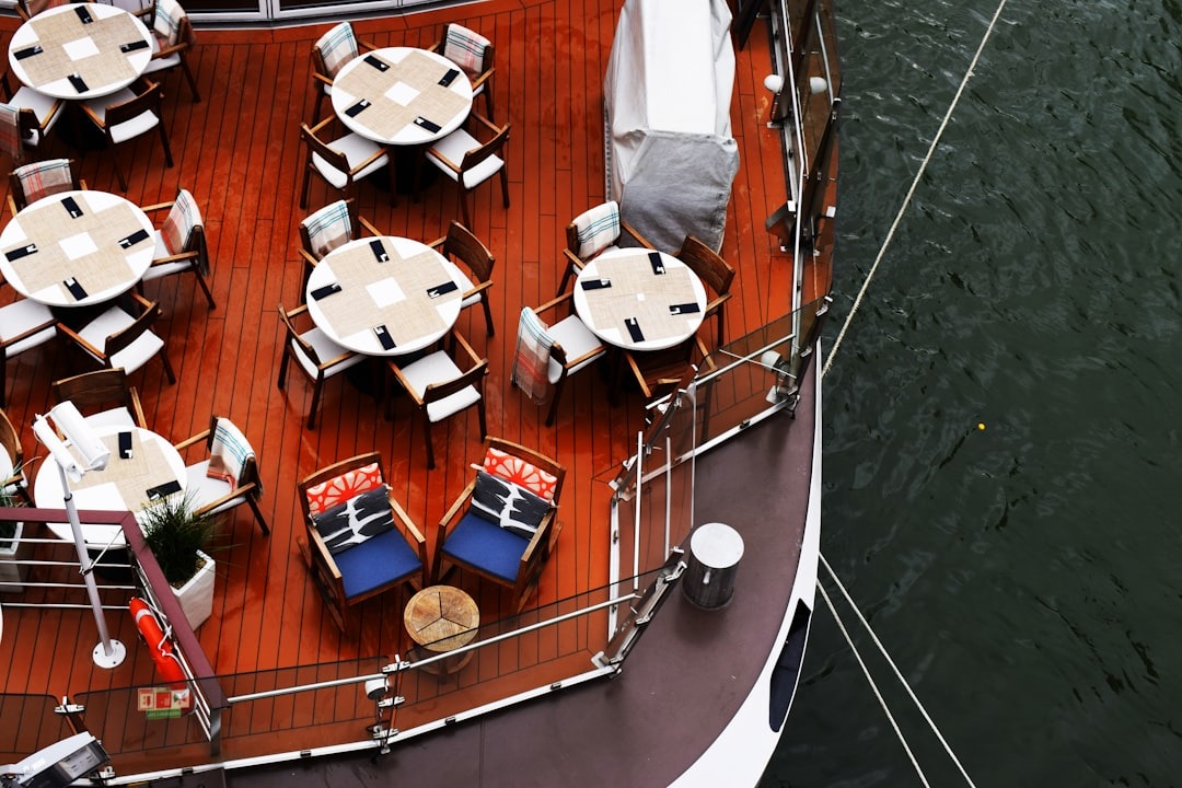Empty dining tables arranged on a wooden boat deck.