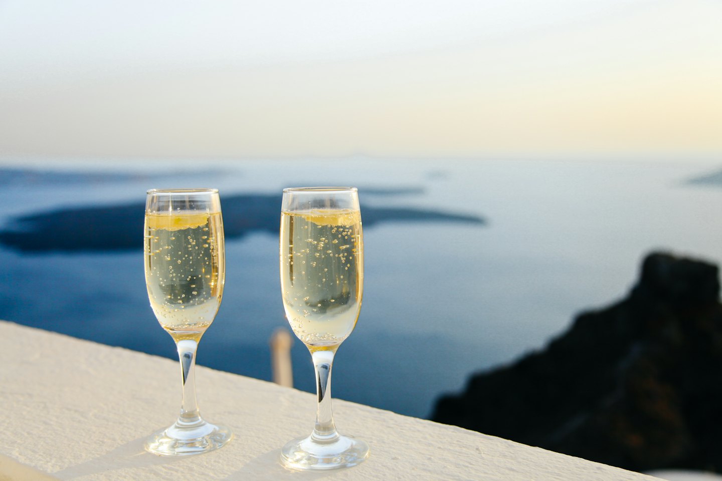 Champagne flutes toasting with ocean view.