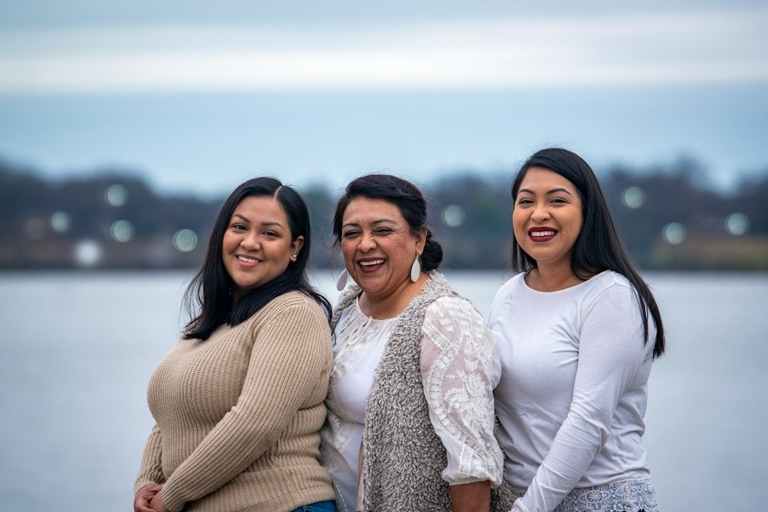 Three smiling women posing together outdoors.